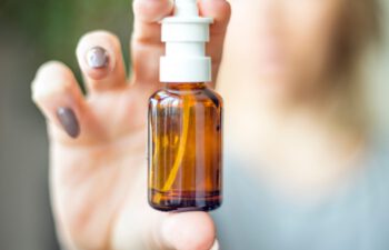 Nasal Spray, Female hand spraying nasal spray with blurred background. Medicine and health care concept. Antivirus treatment.